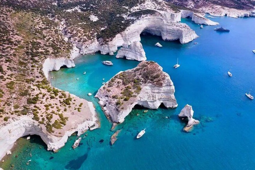 A coastal landscape with white cliffs, clear turquoise waters, and boats. 3