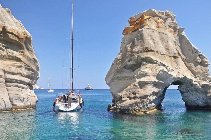 A boat navigating through a natural rock arch in clear waters. 2