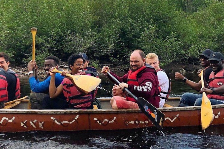 A group of people in a canoe on a river, wearing life jackets. 5
