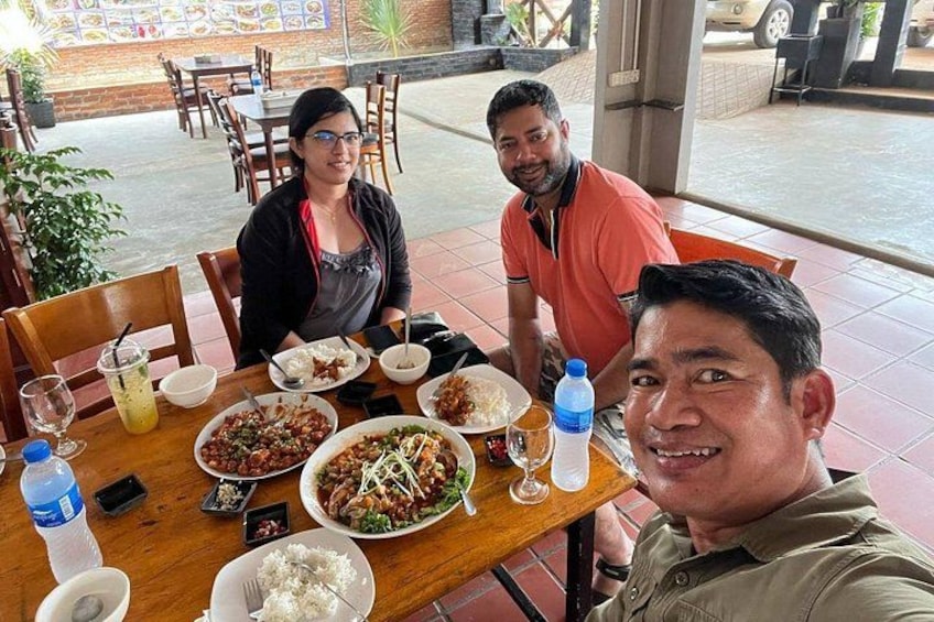 A group of people dining at an outdoor restaurant with various dishes on the table. 4