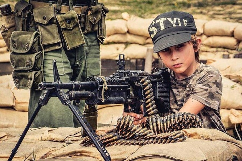 A person in military attire with a machine gun and ammunition. 5
