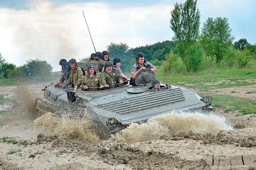 A group of soldiers on a military vehicle driving through a muddy field. 4