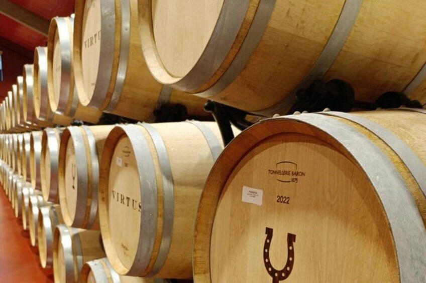 Rows of wooden wine barrels with metal bands and labels, including one marked '2022' and 'TONNELLE BARON.' 4
