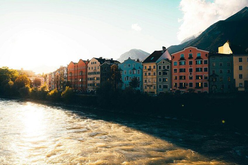 Une rivière bordée de bâtiments, une montagne en arrière-plan et le soleil se couchant ou se levant. 5