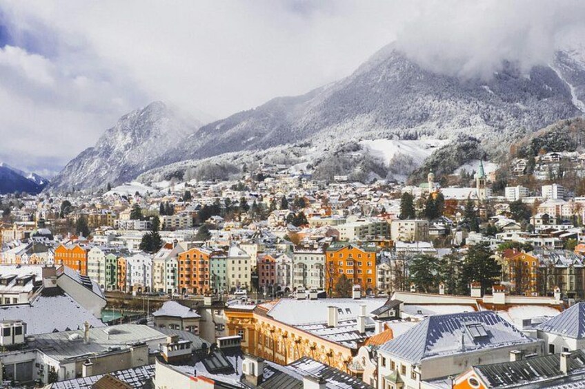 Un paysage urbain avec des bâtiments aux couleurs vives, une montagne en arrière-plan et un terrain enneigé. 4