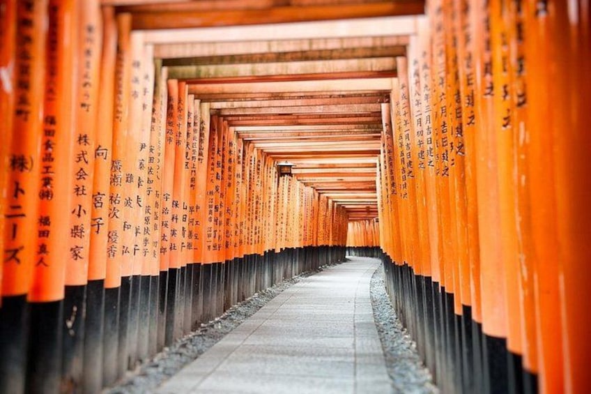 Een gang omlijst door oranje torii-poorten die naar een schrijn leiden. 1