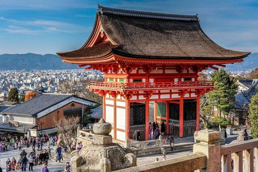 Een traditionele Japanse tempel met een rood dak, omgeven door een stenen fundering en een menigte mensen. 2