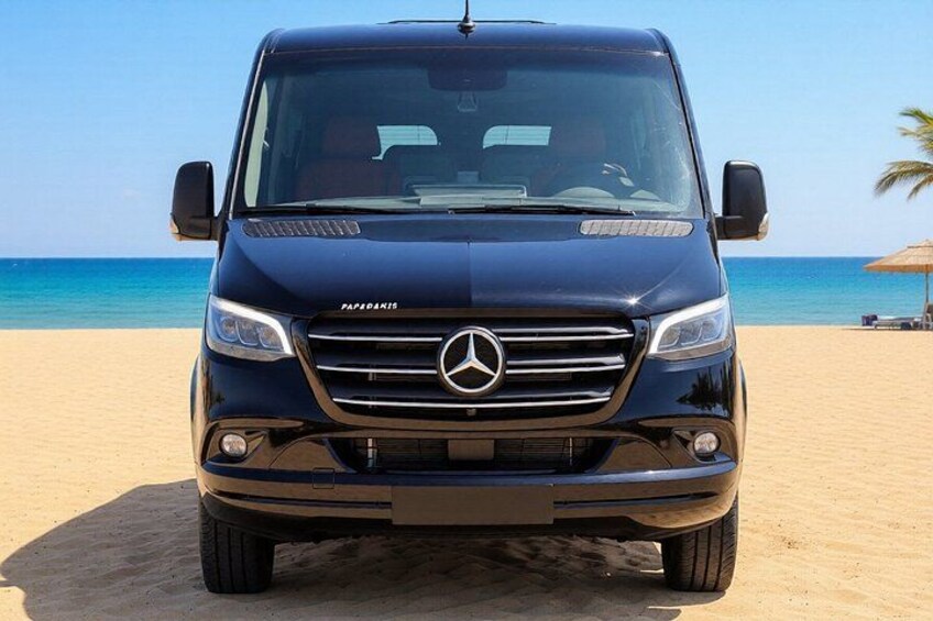 Una furgoneta negra Mercedes-Benz estacionada en una playa arenosa, con el océano al fondo. 4