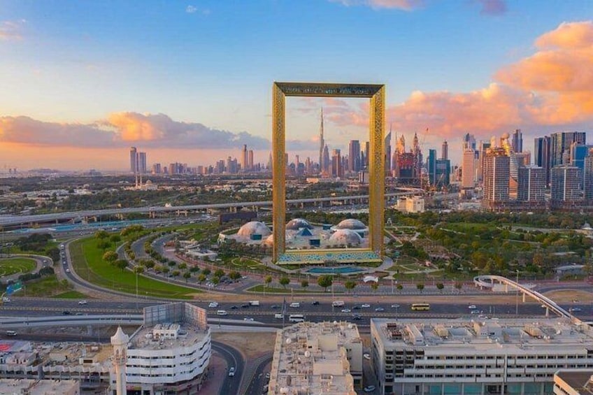 A cityscape with a prominent golden frame structure, a mosque, and a modern skyscraper. 3