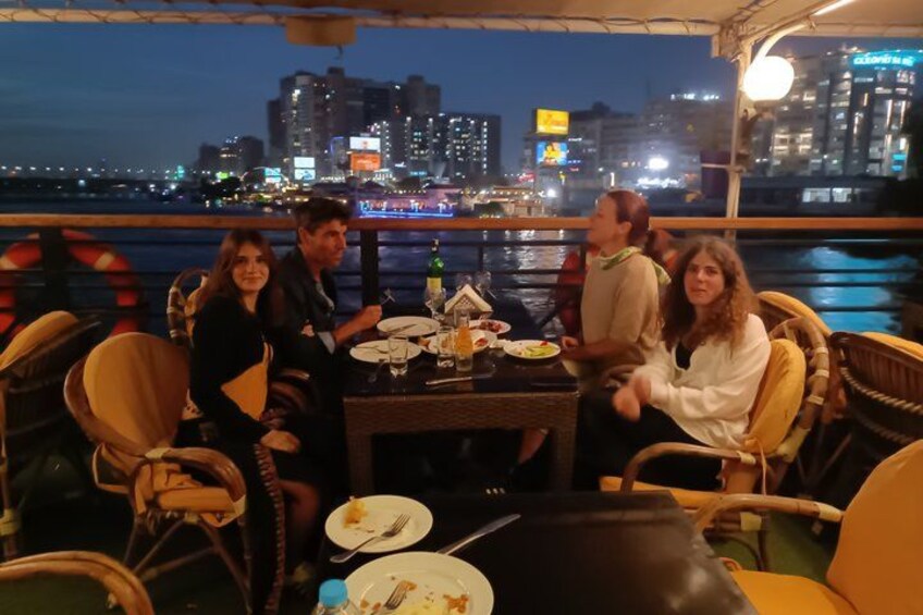A group of people dining on a boat with a city skyline in the background. 4