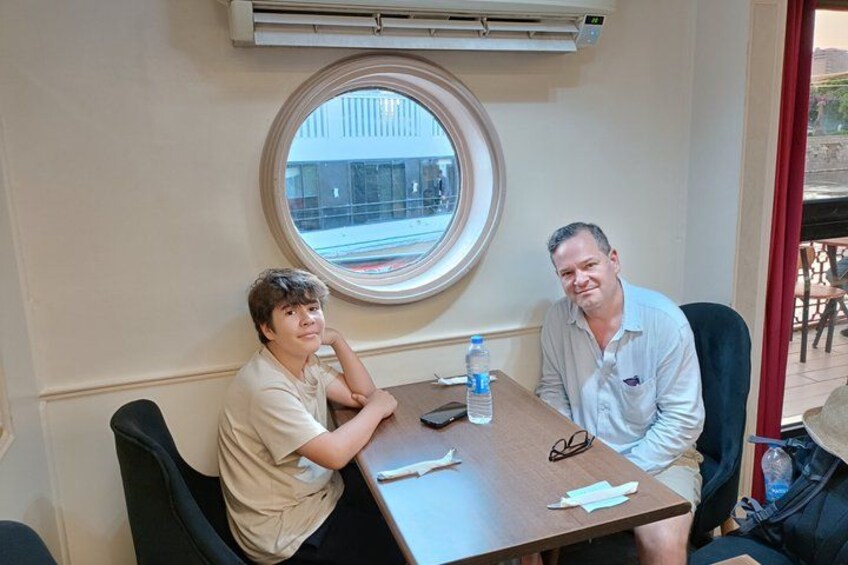 Two people sitting at a table with a bottle of water and a pair of glasses on it. 5