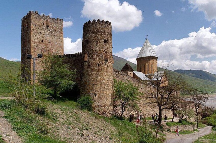 A medieval stone castle with two towers and a church with a dome. 4