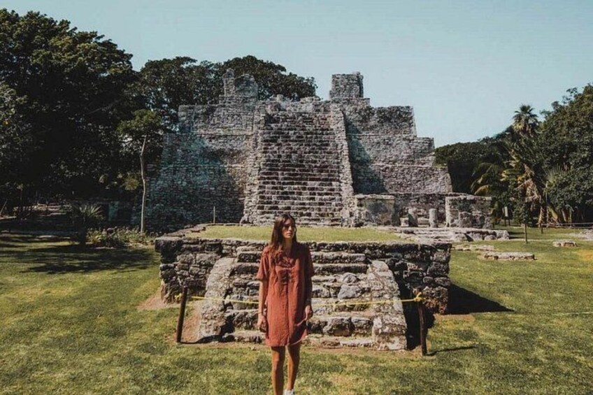 Una persona de pie frente a unas ruinas mayas antiguas con una estructura piramidal. 1