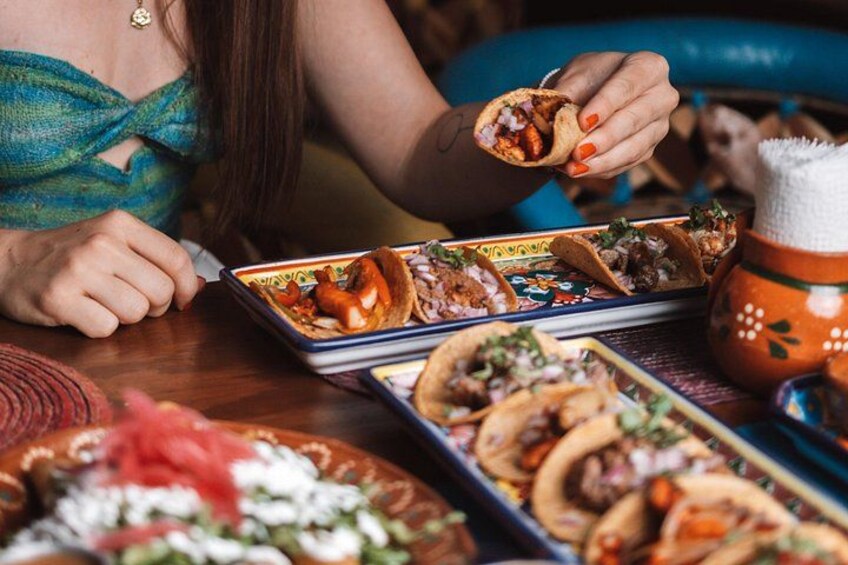 Una persona sosteniendo un taco, con un plato de tacos y un tazón de arroz a la vista. 4