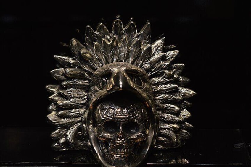 A metallic sculpture with a floral pattern and a central face. 3