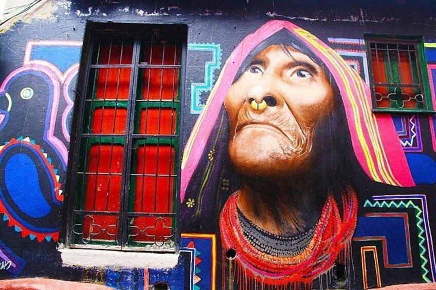 A mural with a person wearing a colorful headdress and a necklace, a window with red bars, and a colorful geometric pattern on the wall. 3
