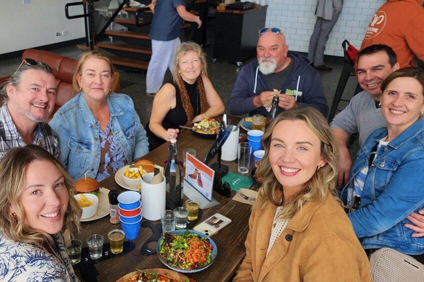 Un grupo de personas sentadas alrededor de una mesa con comida y bebidas. 1