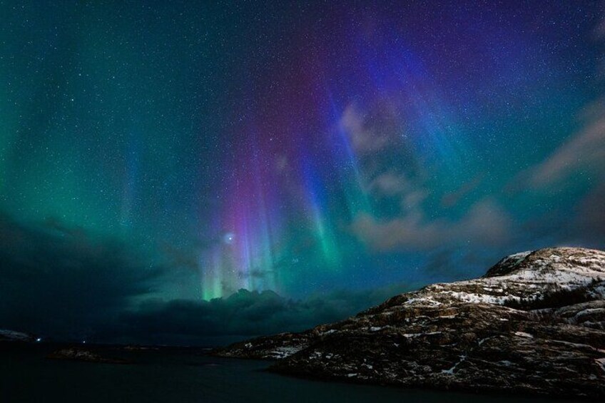 A night sky with the aurora borealis over a rocky coastline. 4