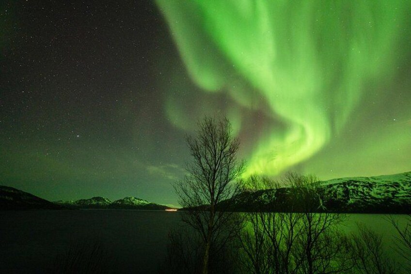A night sky with the Northern Lights over a lake and mountains. 3
