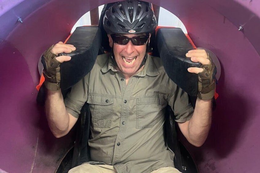 A person in a seat with a helmet and gloves, holding onto the sides. 4