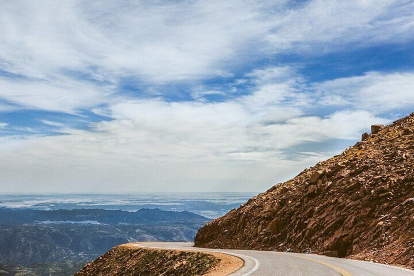 A winding mountain road with a clear sky and distant mountain ranges. 2
