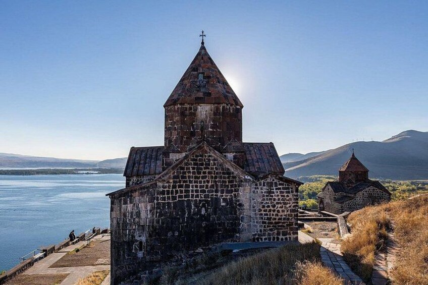 Une église en pierre dotée d’un clocher, située au bord d’un lac et entourée de collines. 3