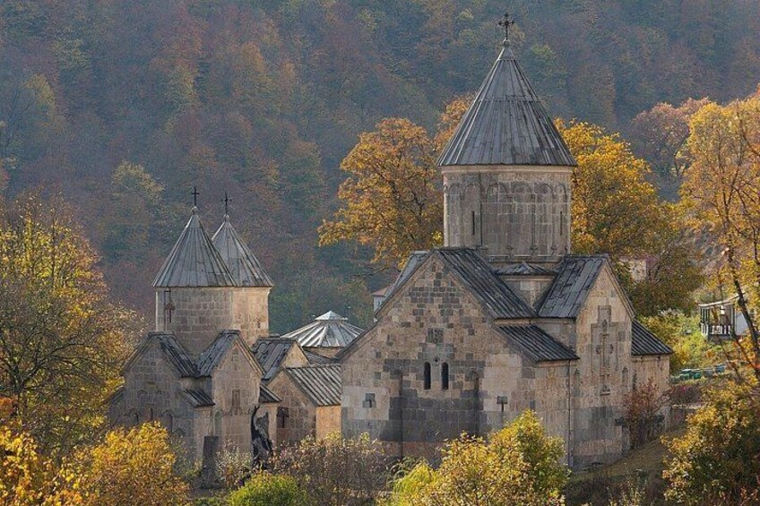 Une église en pierre, dotée de plusieurs coupoles et d’un clocher, entourée d’arbres aux couleurs automnales. 5