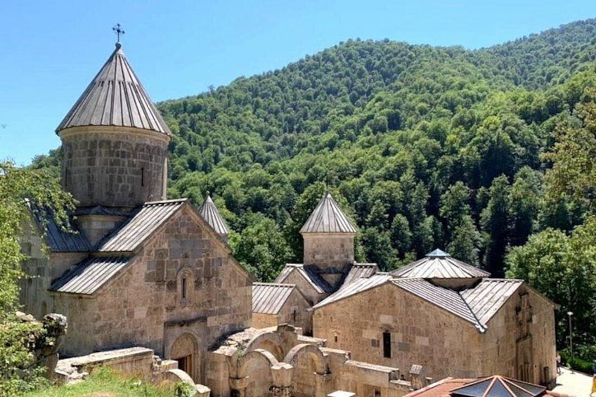 Une église en pierre dotée d’un clocher et de bâtiments plus petits, entourée d’une colline boisée. 4