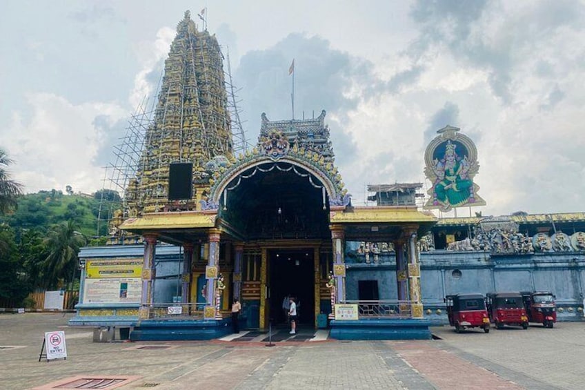 A temple with a large spire, a deity statue, and a signboard. 4