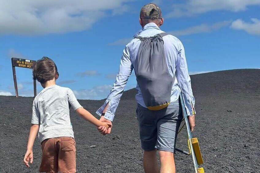 Een man en een kind houden hand in hand in een vulkaanlandschap. 5