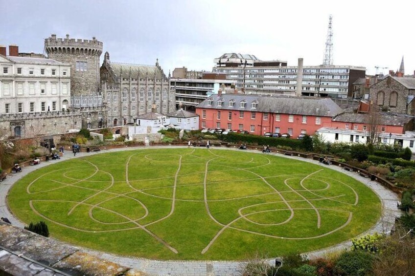 A historic castle with a large lawn in the center, surrounded by modern buildings. 5