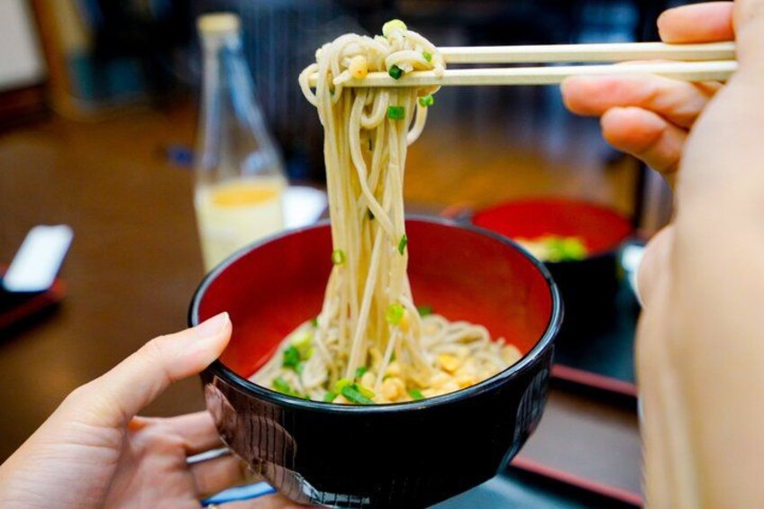 A bowl of noodles being lifted with chopsticks. 4