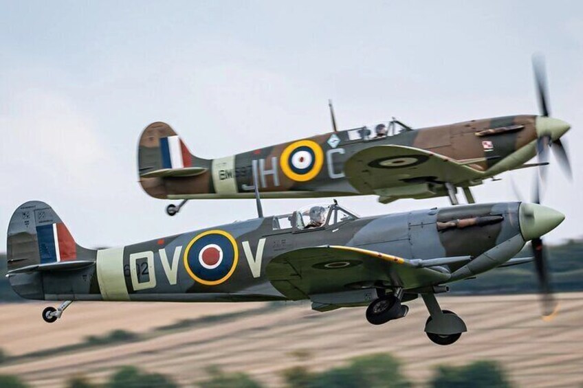 Two military aircraft in flight, one with a roundel and the other with a camouflage pattern. 1