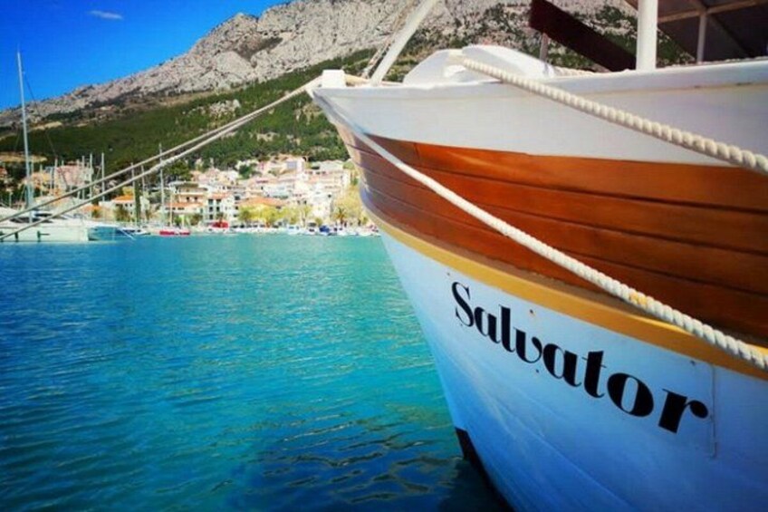 A boat named 'Salvator' docked at a harbor with a mountainous backdrop. 3
