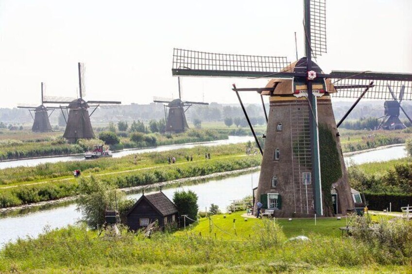 A windmill with a water wheel, surrounded by green fields and a river. 1