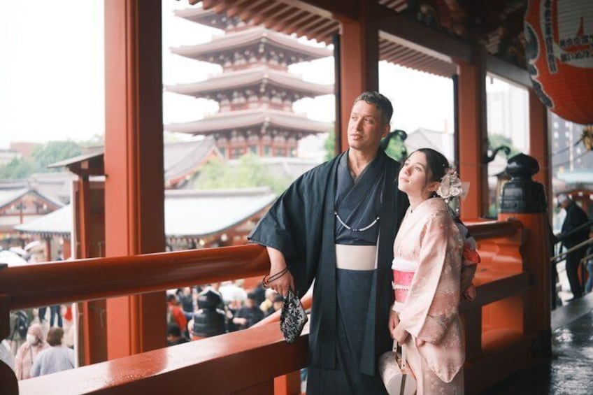 A traditional Japanese couple in kimonos standing on a bridge with a pagoda in the background. 2