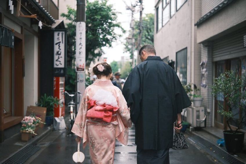 A narrow street with traditional buildings, a person in a kimono, and another in a dark jacket. 4