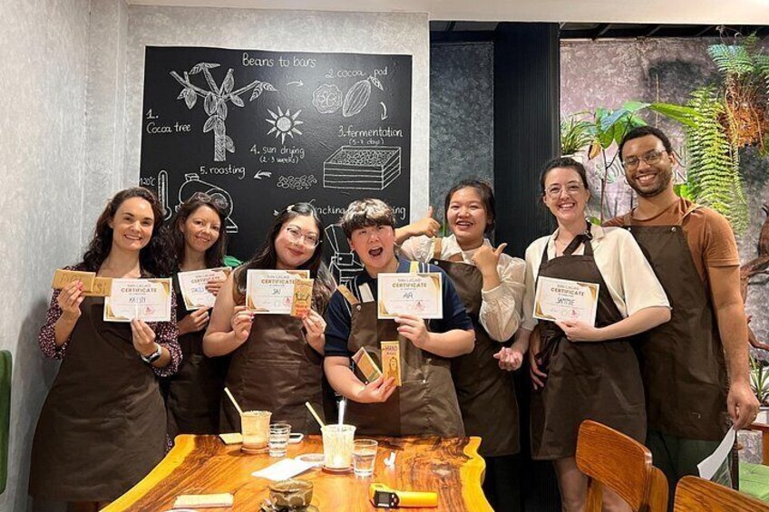 Un grupo de personas sosteniendo certificados, frente a una pizarra con dibujos sobre café. 2