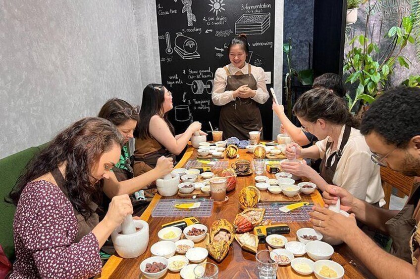 Un grupo de personas sentadas alrededor de una mesa con diferentes platos, y un chef de pie al fondo. 1