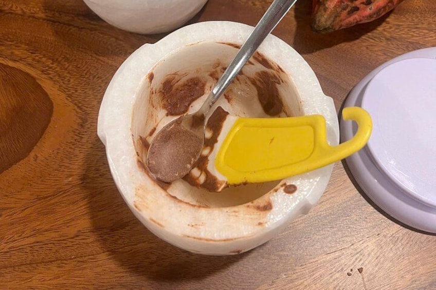 Un tazón blanco con una cuchara y un utensilio amarillo sobre una mesa de madera. 4