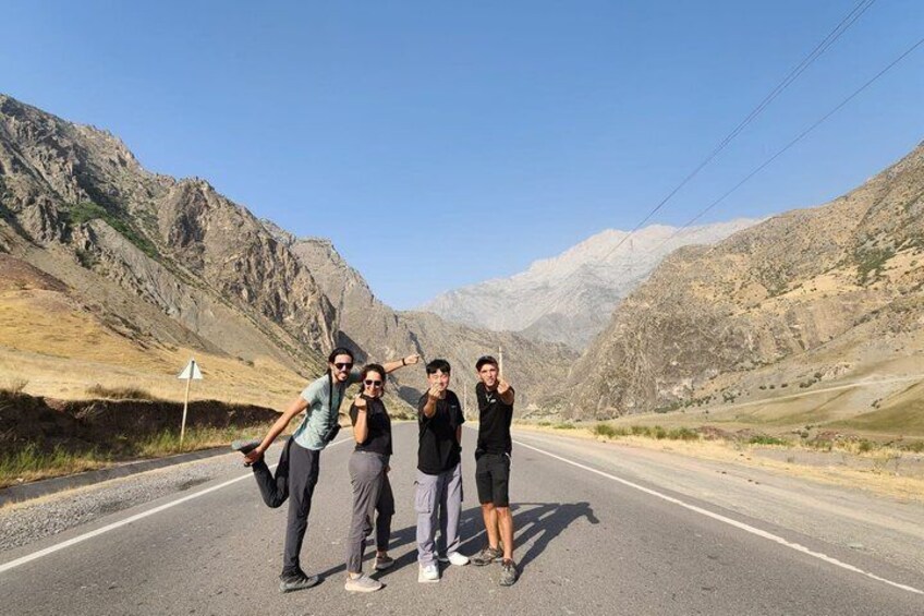 A group of people on a road with mountainous terrain in the background. 4