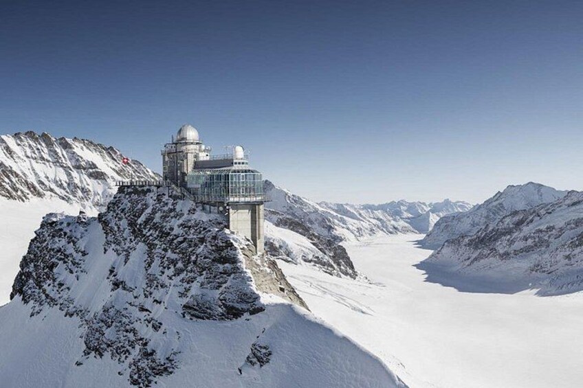 Paisaje montañoso nevado con un gran observatorio en un promontorio rocoso. 1