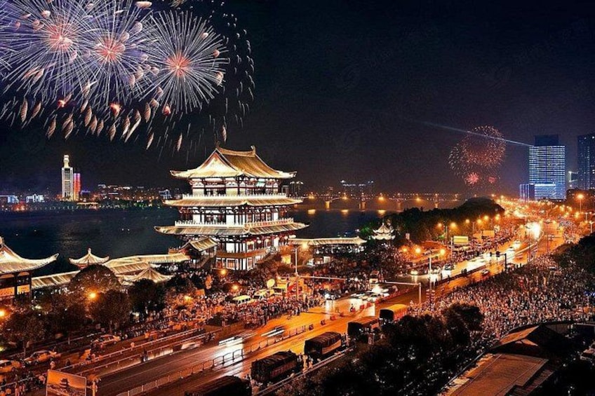 Un edificio tradicional con varios niveles, un río y fuegos artificiales al fondo. 1
