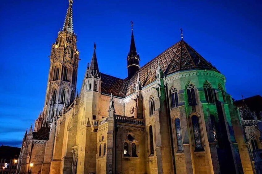 Een historisch kathedraal met een hoge toren en een geel verlichte gevel. 5