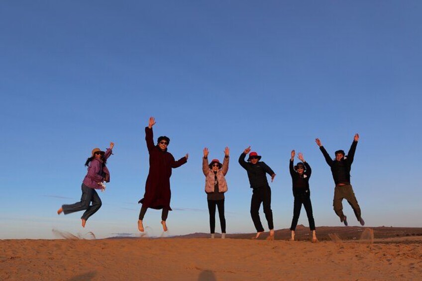 A group of people jumping in the air on a desert landscape. 3