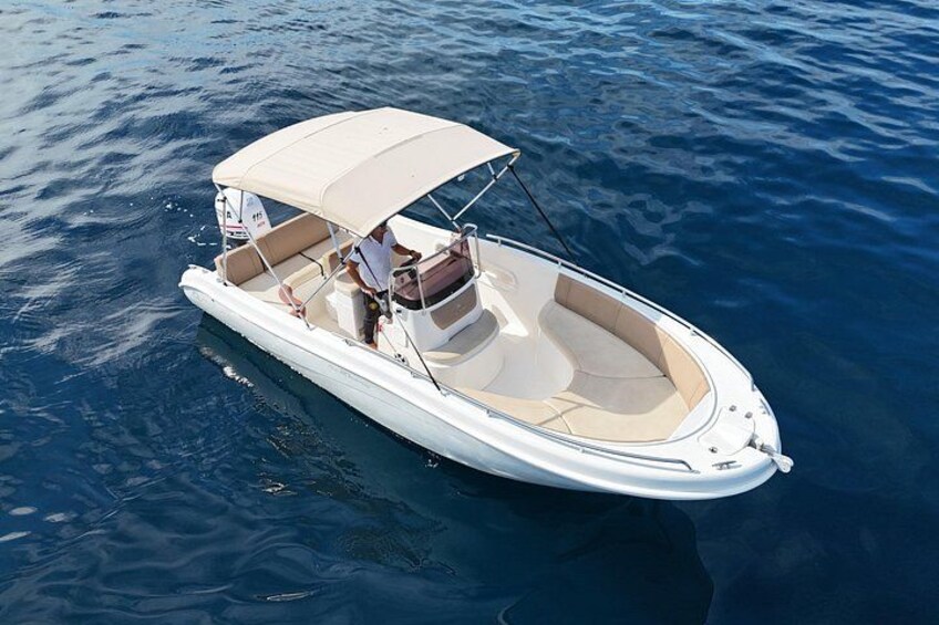 A white motorboat with a canopy, floating on calm water. 2