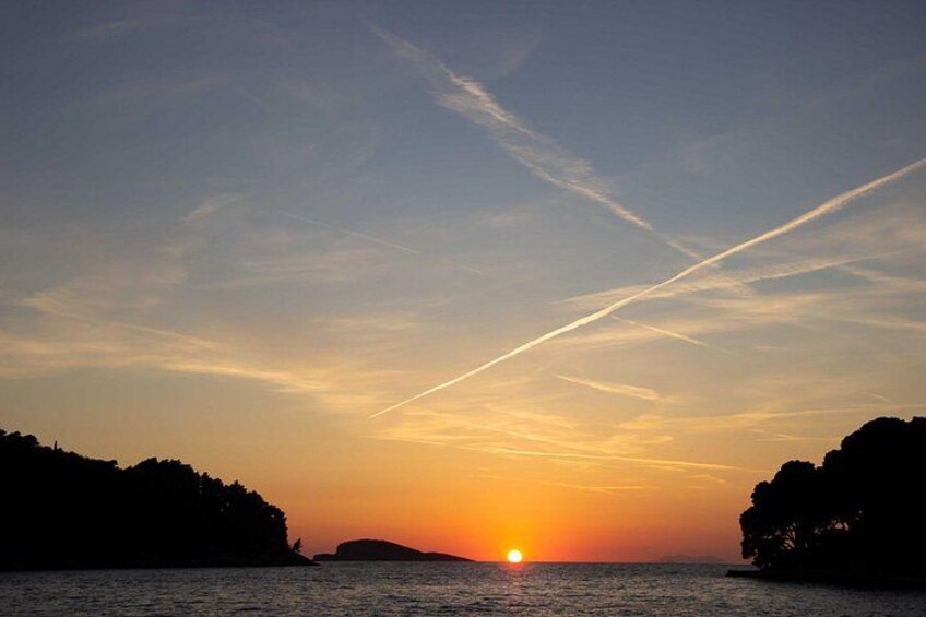 A sunset over a body of water with silhouetted landforms on either side. 4