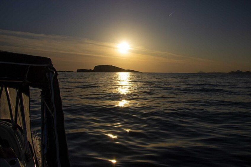 A sunset over water with a boat in the foreground. 5