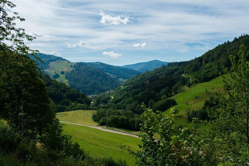 A valley with a road, green fields, and forested hills. 3