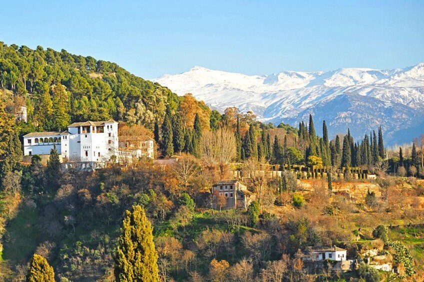 A mountainous landscape with a white building, trees, and snow-capped peaks. 3